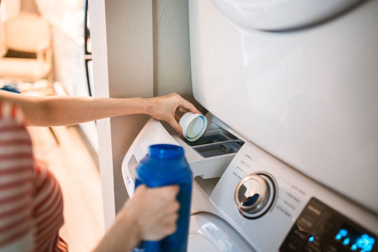 digital Close-up of a person pouring detergent into a front-loading washer, emphasizing household chores.